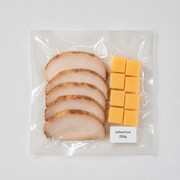 Sliced roast meat and cheese cubes in a clear vacuum pack with a Chilled Food 220g label