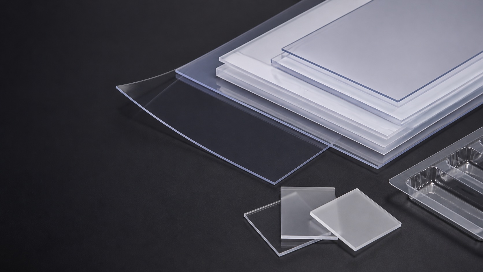 Wide semi-rigid PS thermoforming sheet stack with clear cut swatches on a dark studio background